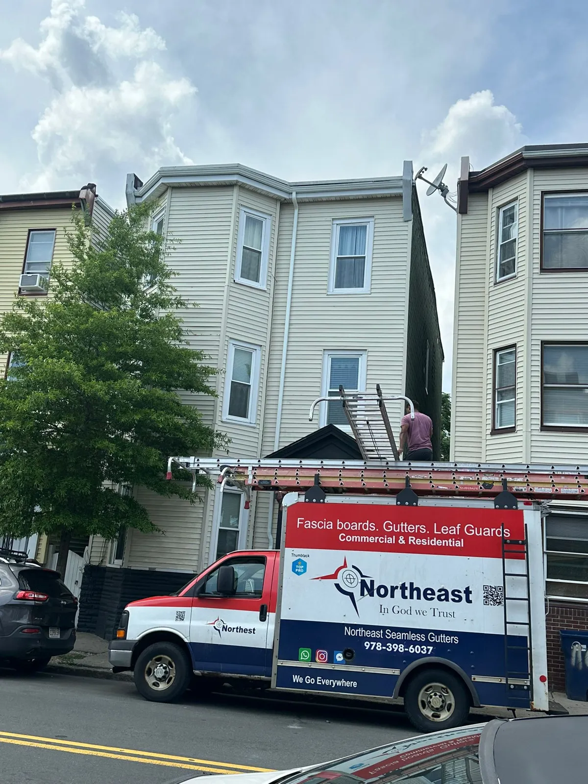 Northeast Seamless Gutters service truck parked outside a three-story home