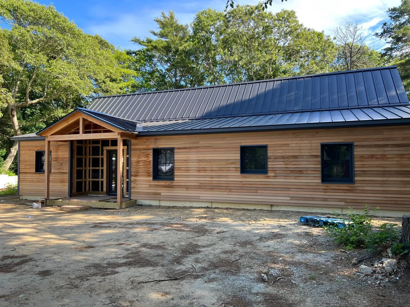 Single-story cedar-sided home with a dark standing seam metal roof