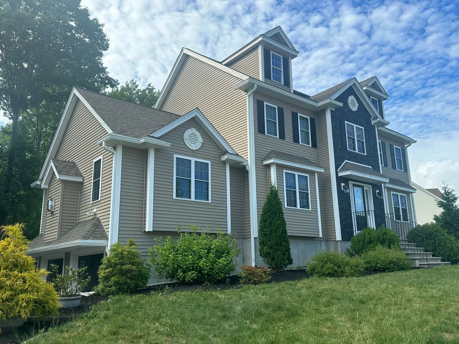 Two-story tan home with white gutters and downspouts