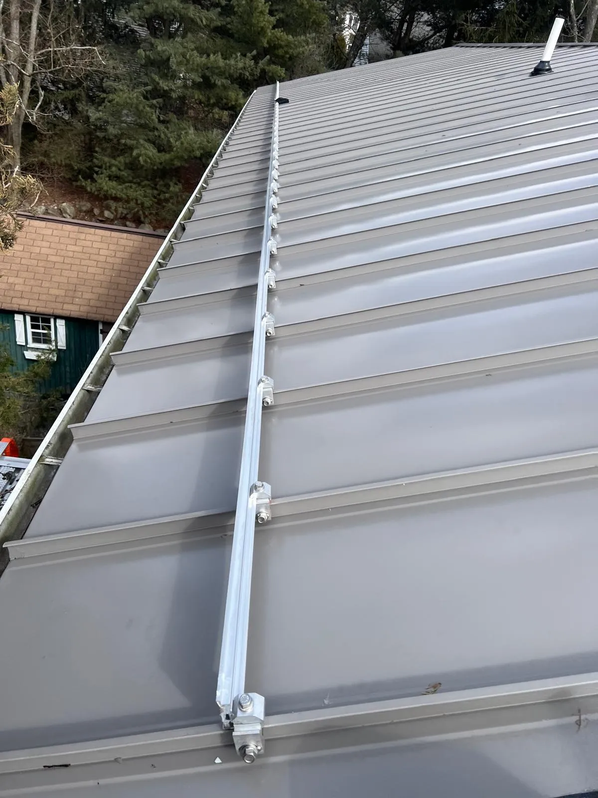 Light-gray standing seam panels running down to the eave