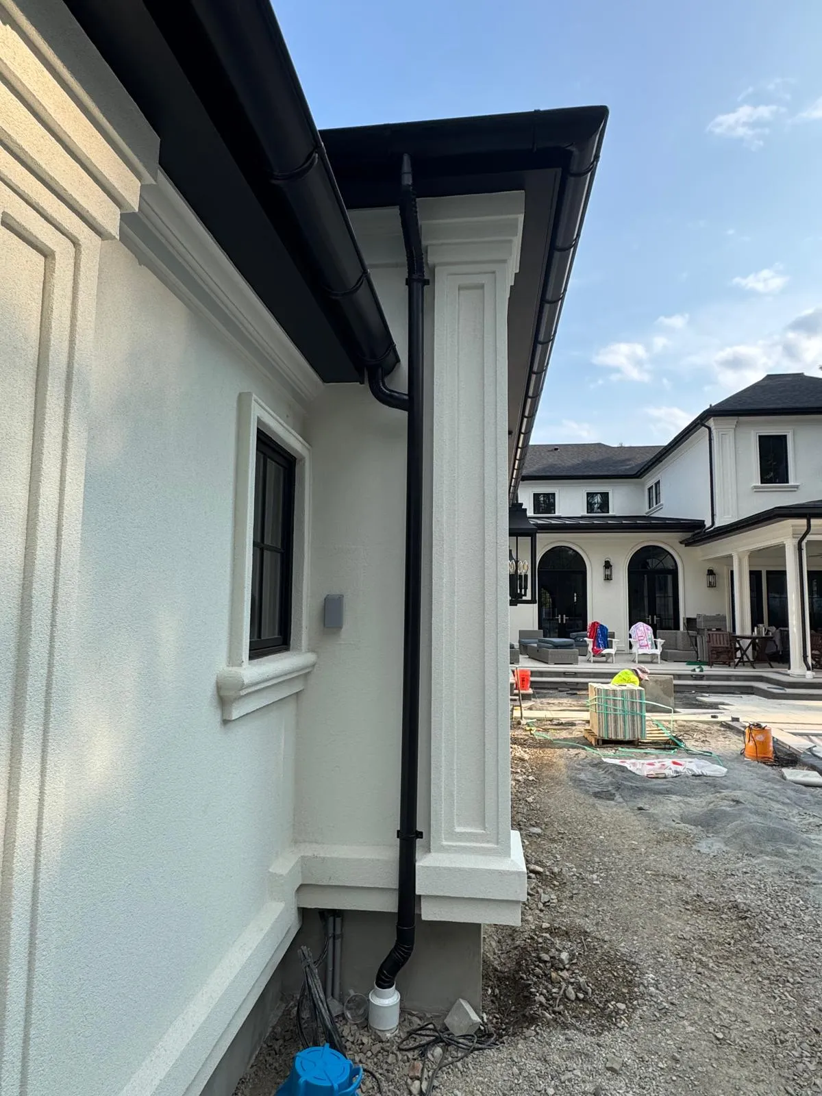 Dark gutter and downspout down a white wall corner
