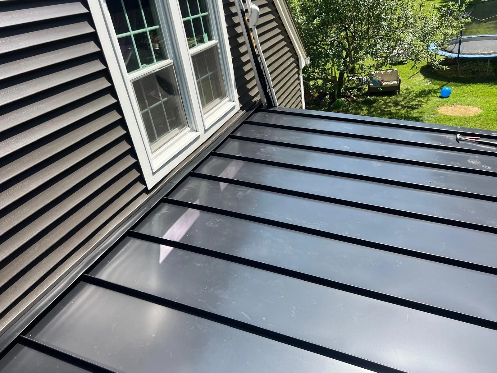 Finished standing seam metal roof below a window