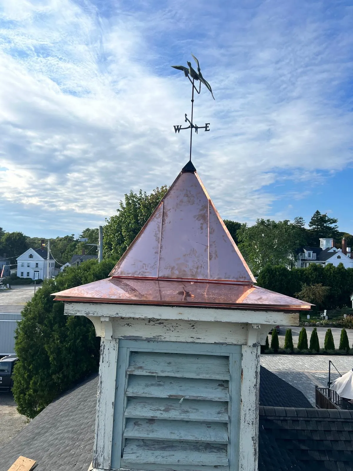 Finished copper cupola roof with a weathervane against blue sky