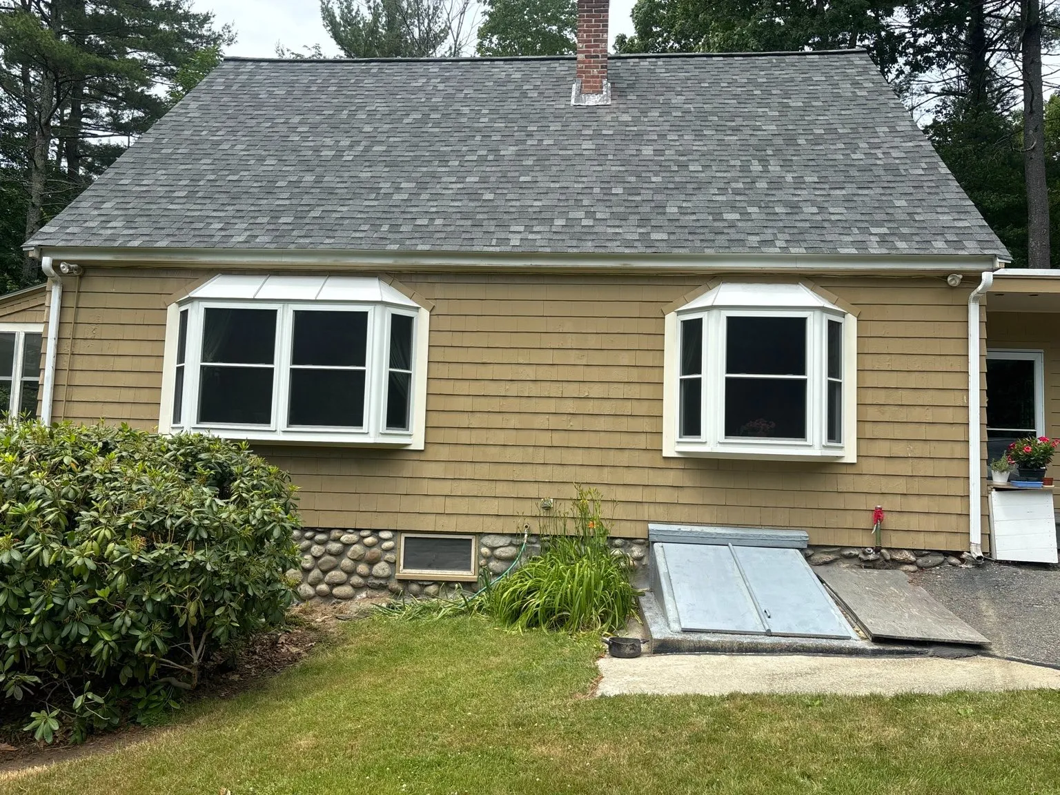 Cape-style home with bay windows and white gutters