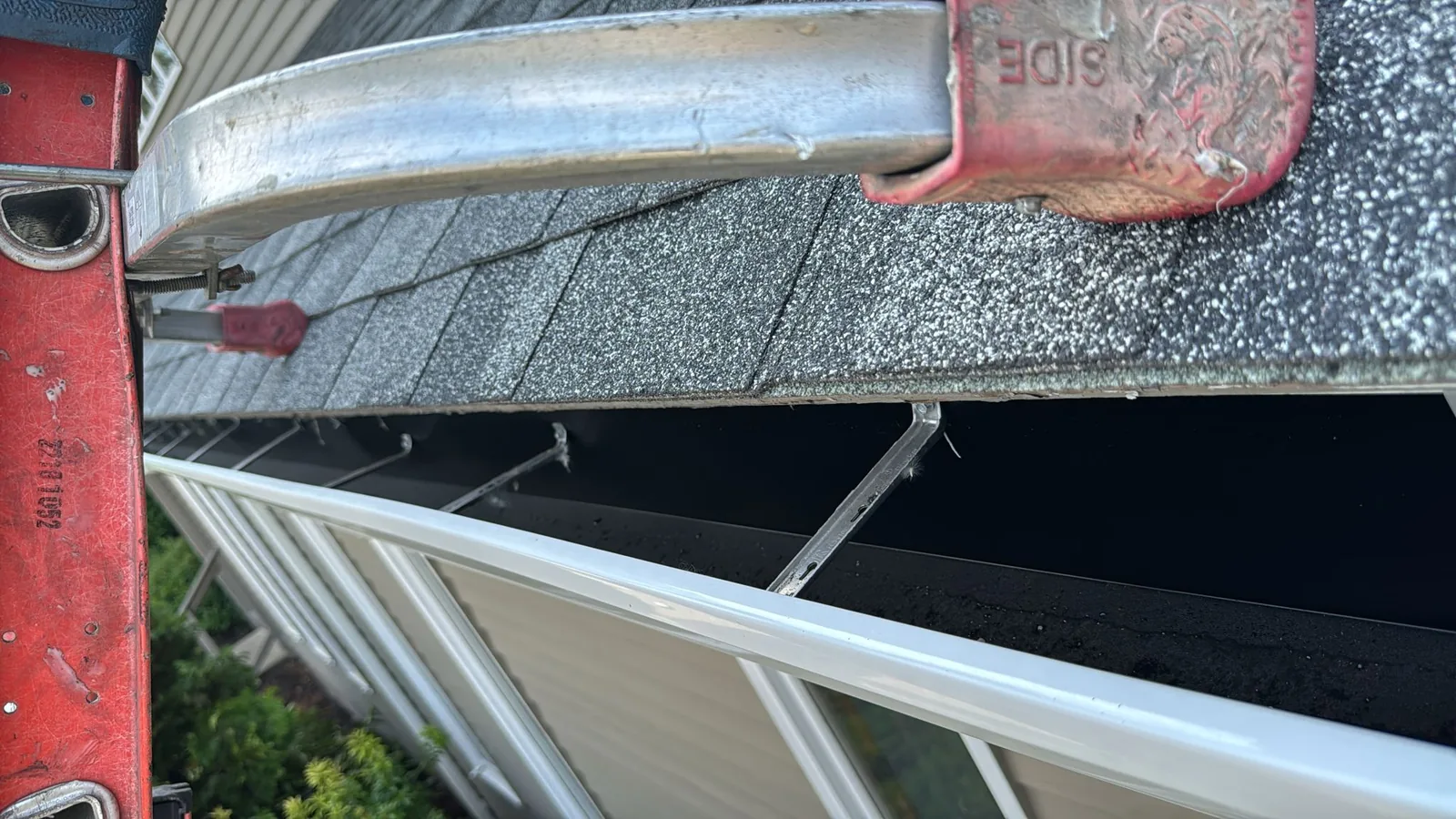 Close-up showing installation of a white gutter with metal mounting details