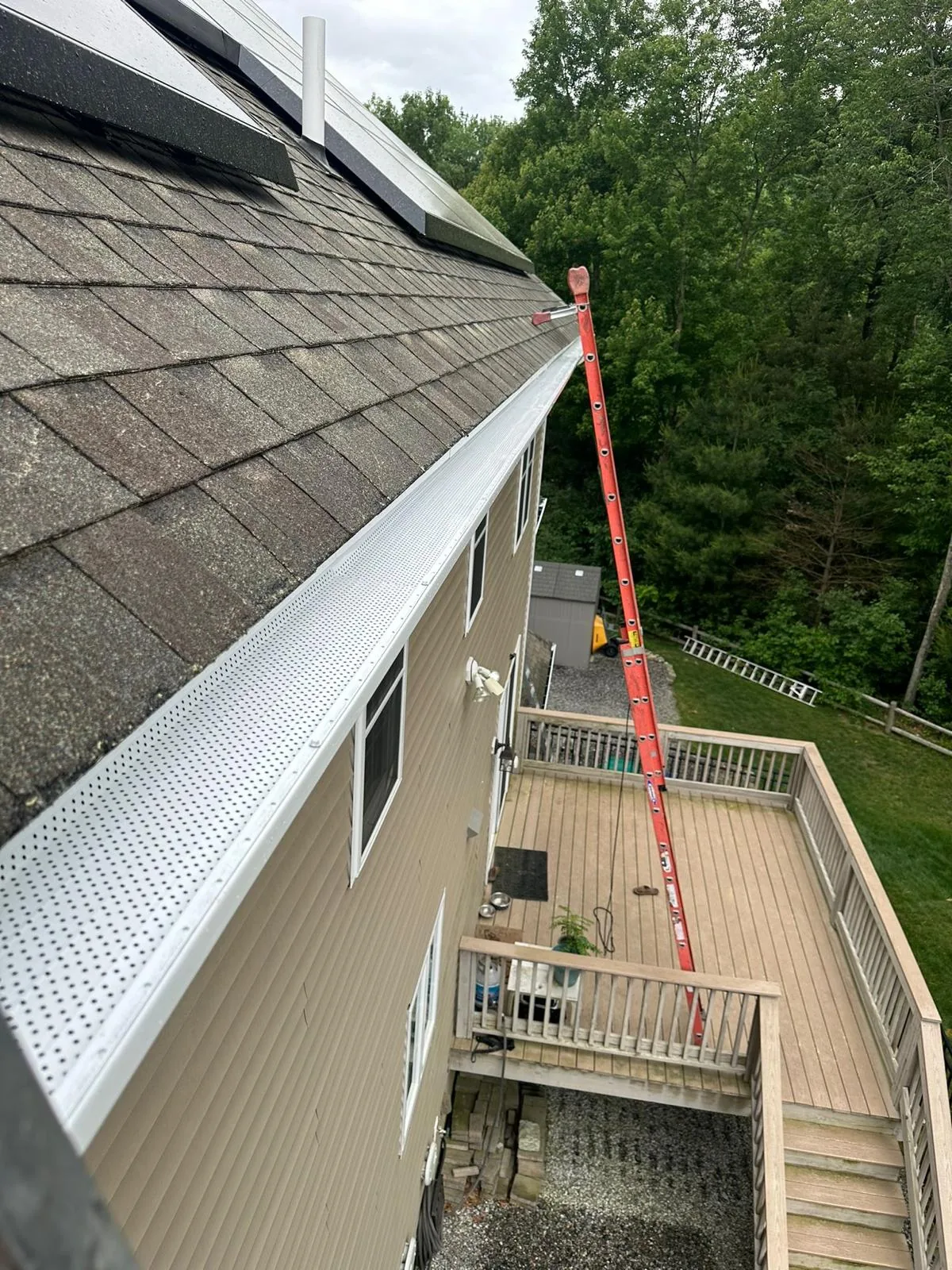 White gutter guard installed along a shingled residential roofline